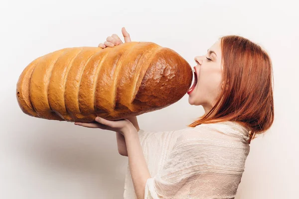 Side view of beautiful red-haired woman with fresh loaf in hands — Stock Photo, Image