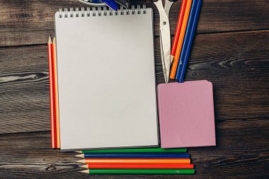 Not defterleri renkli kalemler tahta arka plan görünümünde makas.