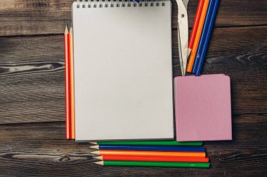 Not defterleri renkli kalemler tahta arka plan görünümünde makas.