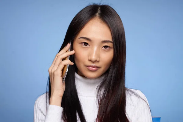 Asyalı kadın bacakları mavi arka plandaki stüdyoda telefonla konuşuyor. — Stok fotoğraf