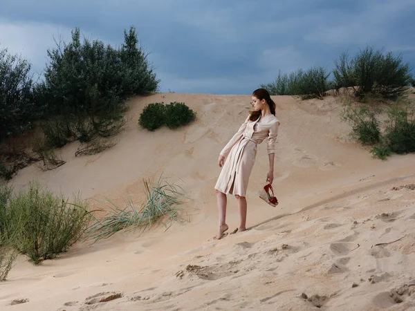 Mujer en un vestido ligero en la playa en la arena zapatos rojos modelo —  Fotos de Stock