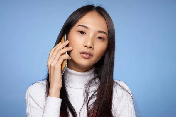 Mujer asiática hablando en un teléfono celular sobre un fondo azul — Foto de Stock