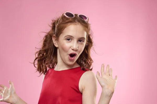 Menina alegre infância óculos escuros vestido vermelho estilo de vida fundo rosa — Fotografia de Stock