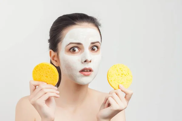 emotional woman with sponges in hands cream mask on face cropped view