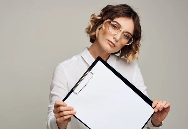 Dossier avec une feuille blanche de papier sur fond gris dans les mains d'une maquette de femme — Photo