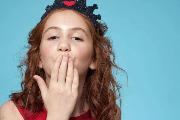 Menina com cabelo encaracolado com uma coroa em sua cabeça vermelho vestido estilo de vida azul fundo — Fotografia de Stock