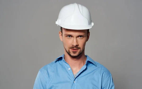 身穿白色头盔、蓝色衬衫、灰色背景情感肖像的建筑师 — 图库照片