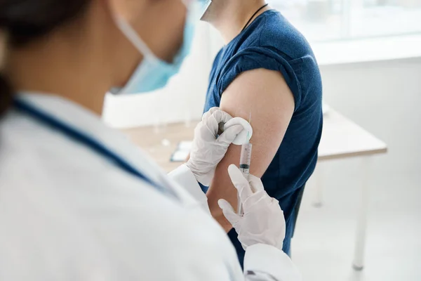 Médico le administra una inyección en el hombro paciente con camiseta paciente covid vacunación — Foto de Stock