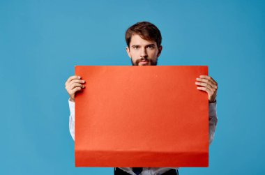 Kırmızı bayrak taşıyan duygusal adam, mavi arka plan reklamları yapıyor.