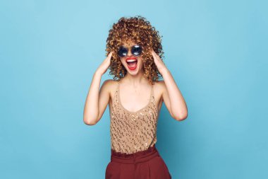 Çekici model kıvırcık saçlar, açık ağız güneş gözlüğü cazibesi. 