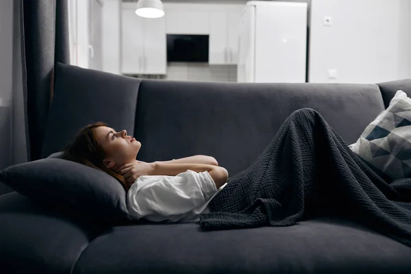 Mujer cubierta con una manta está descansando acostado en el sofá —  Fotos de Stock