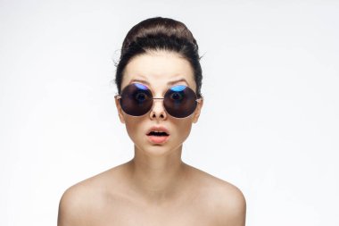 Güzel bir kadın. Çıplak omuzlar. Güneş gözlüğü. Işık arka plan.