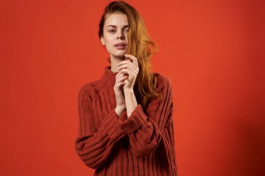 Kırmızı süveter giyen neşeli, duygusal kadın. Kırmızı arka plan gündelik giyimi.