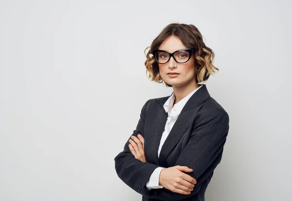 Una donna d'affari in occhiali e in giacca e cravatta su uno sfondo chiaro incrociava le braccia sul petto — Foto Stock