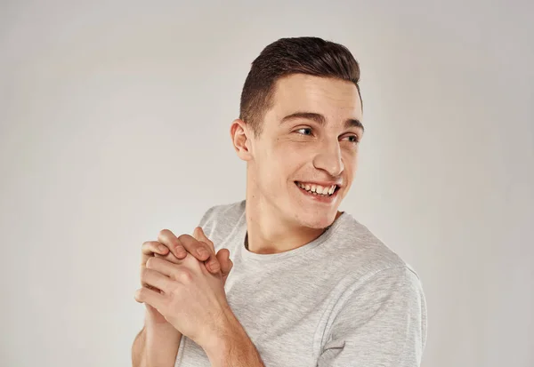 Een vrolijke man in een wit T-shirt gebaart met zijn handen emoties close-up — Stockfoto