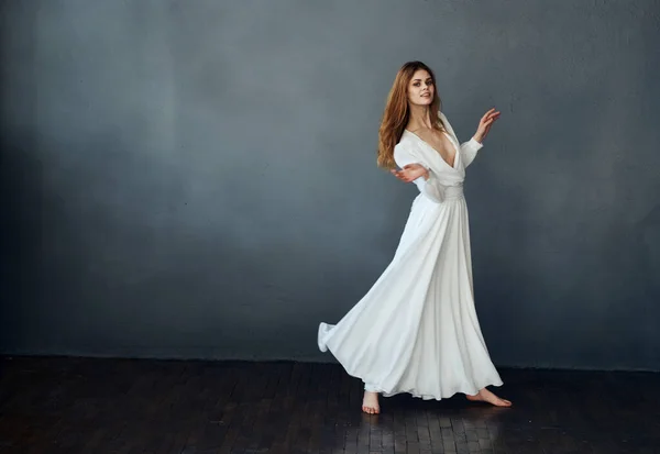 Senhora encantadora em um vestido branco em um fundo cinza dança gesticulando com as mãos Copiar modelo de espaço — Fotografia de Stock