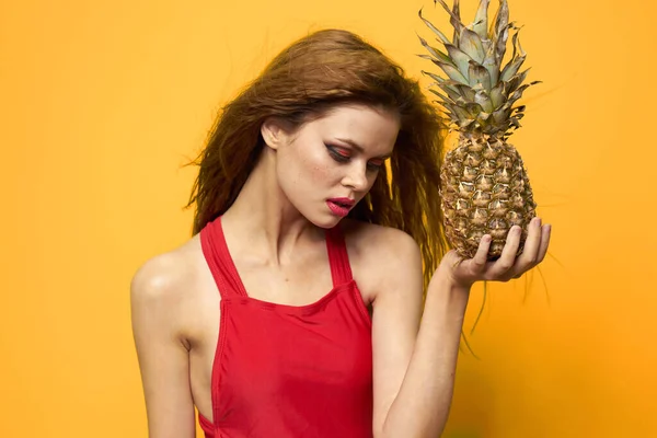 Vacker kvinna i röd t-shirt Ananas i händer Exotisk gul bakgrund — Stockfoto
