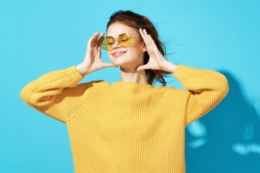 Sarı süveter giyen neşeli bir kadın. Keyifli mavi bir arka plan.