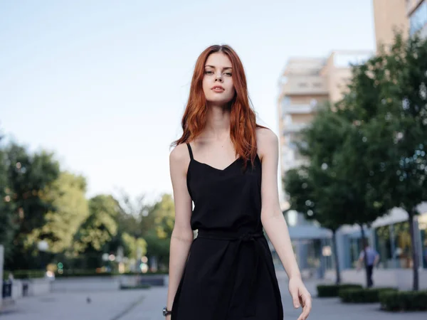 Модная женщина в черном платье гуляет по улице в парке на природе — стоковое фото