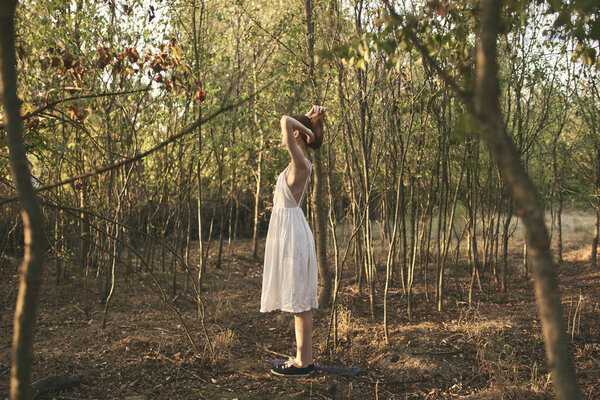 A woman in a white dress walks in the forest in full growth. High quality photo