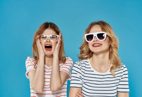 Twee vrouwen in gestreepte T-shirts emoties vreugde communicatie vriendschap levensstijl blauw achtergrond — Stockfoto