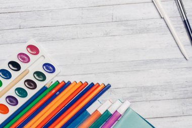 Tahta kart tutacağı kalemler ve suluboya boyalar üzerine kırtasiye.