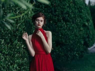 Güzel kadın kırmızı elbise kozmetik çekici yeşil çalı karnavalı