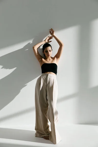 Mulher elegante em roupas da moda com braços levantados encostados à parede comprimento total — Fotografia de Stock