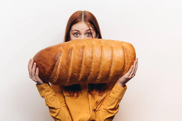 Mulher feliz com um pão na mão um pão em uma posição horizontal em um fundo leve — Fotografia de Stock