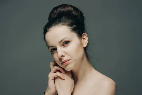 Nackte Frau mit Frisuren im Kopf berührt ihr Gesicht mit den Händen auf grauem Hintergrund — Stockfoto
