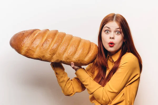 Mulher emocional com um enorme pão em um fundo leve divertido farinha produto — Fotografia de Stock