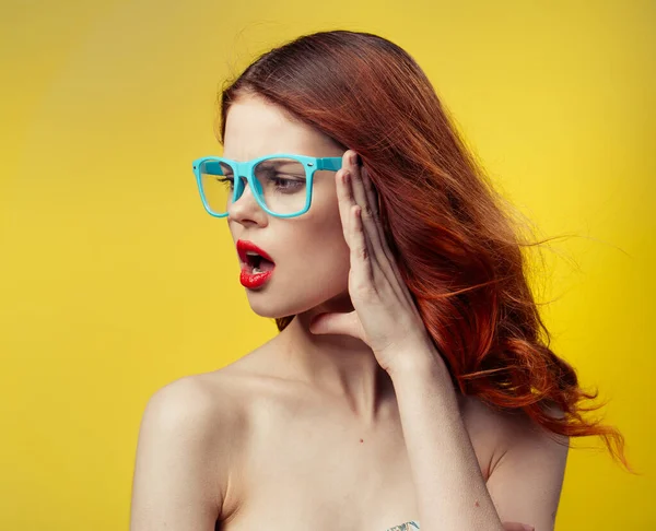 Sarı arka planda mavi gözlüklü kadın portresi — Stok fotoğraf