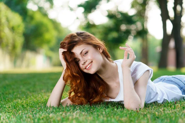 Kvinna ligger i parken på gräsmattan i den friska luften — Stockfoto