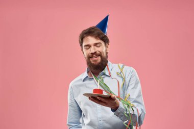 Pembe arka planda mumu olan pastalı bir adamın doğum günü.