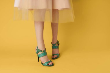 Dişi ayaklar yeşil ayakkabılar zarif stil moda ayakkabılar sarı arka plan