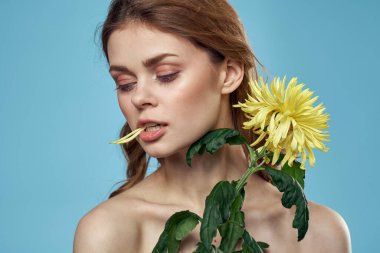 Çiçeklerle süslenmiş kız portresi. Kapalı yay, çıplak omuzlar. Makyaj.