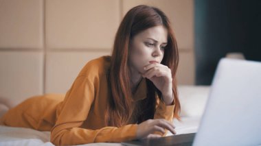 Güzel bir kadın yatak odasında yatıyor. İnternet üzerinden serbest çalışıyor.