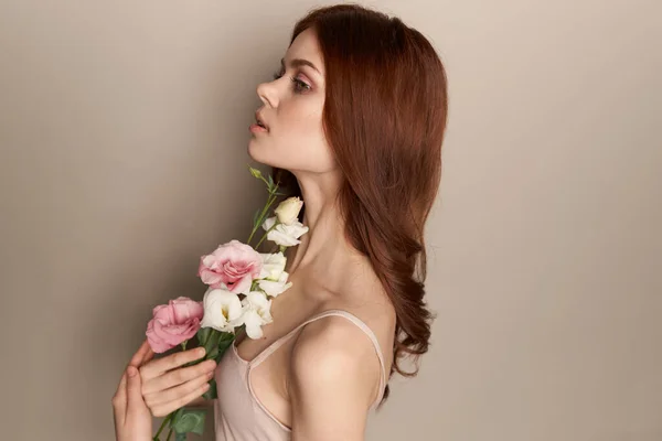 Szczęśliwa kobieta z bukietem lekkich kwiatów na beżowym tle nagie ramiona model rude włosy piękna twarz — Zdjęcie stockowe