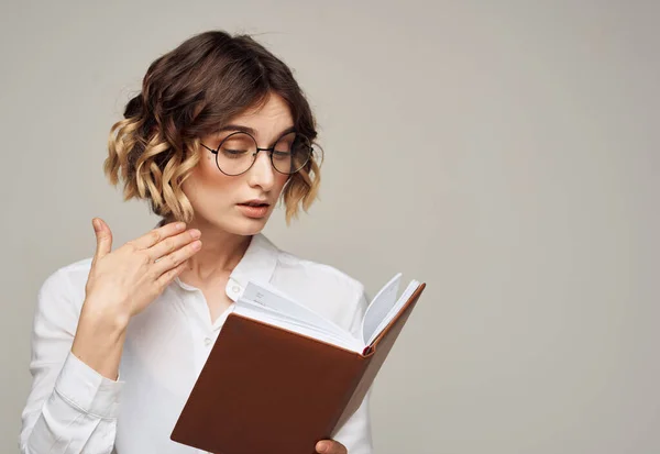 Femme avec bloc-notes sur fond gris à l'intérieur gestuelle avec les mains travail bureau éducation — Photo