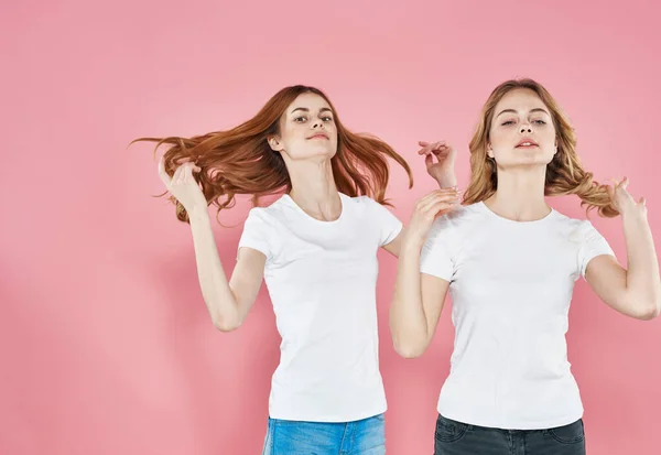 Twee vrouwen modieuze kleding Vriendschap roze achtergrond knuffels — Stockfoto