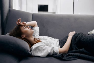 Evdeki kadın kanepede uzanmış, eli ve başı ağrıyormuş.