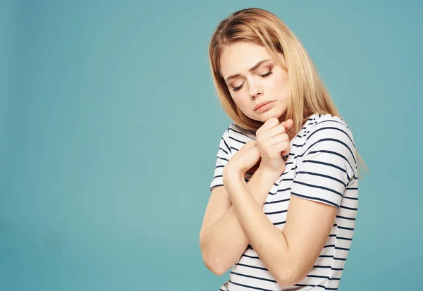 Triste modello donna su sfondo blu in una maglietta a righe mani vicino al viso — Foto Stock