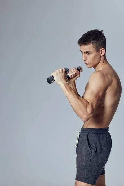 Tipo con inflado cuerpo mancuernas en manos ejercicios de entrenamiento aislado fondo —  Fotos de Stock