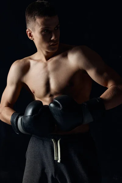Samec sportovec boxerské rukavice na černém pozadí cvičení — Stock fotografie