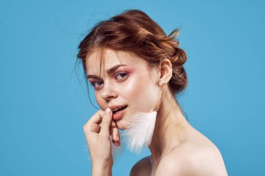 Çekici, çıplak bir kadın. Küpe, makyaj, tazelik, mavi arka plan.