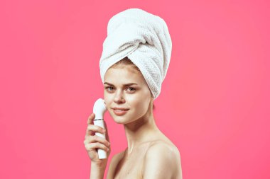 Kafasında havlu olan kadın çıplak omuzlar kozmetik yüz masajcısı.