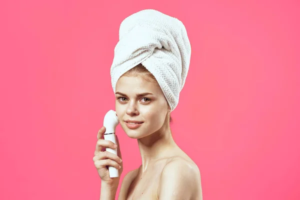 Vrouw met handdoek op hoofd naakte schouders cosmetologie gezicht massager — Stockfoto