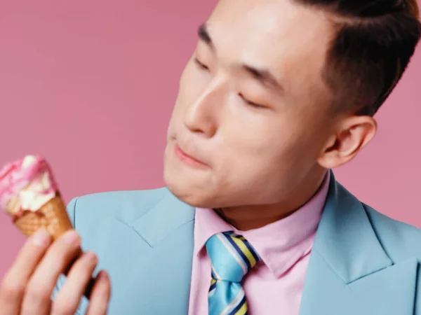 ピンクの背景にアイスクリームを手にしたアジア人男性 — ストック写真