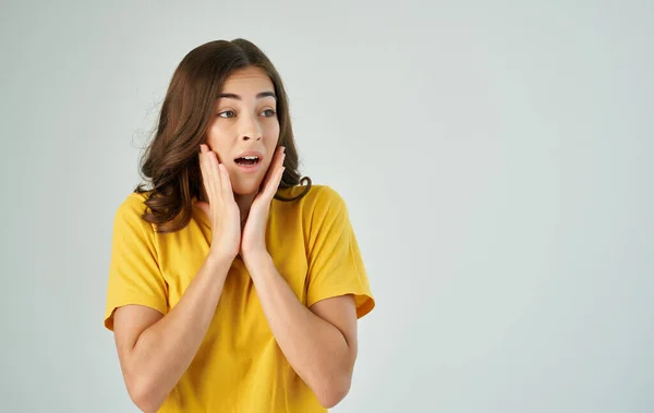 Donna emotiva in giallo t-shirt tenendo i capelli studio vista ritagliata — Foto Stock