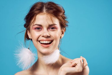 Çekici, çıplak bir kadın. Küpe, makyaj, tazelik, mavi arka plan.